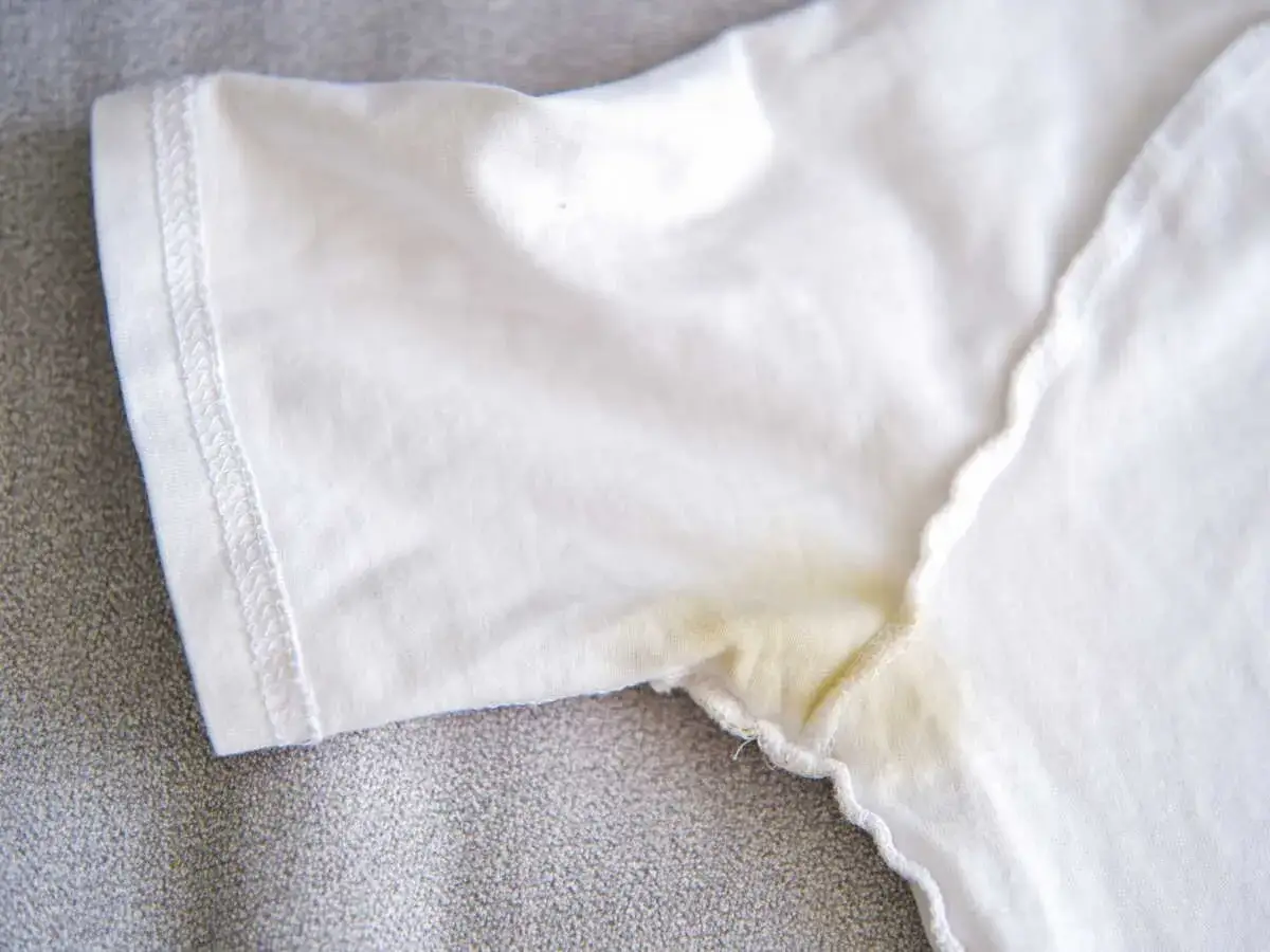 T-shirt blanc avec une tache jaune sous le bras, signe d'une aisselle jaune due à la transpiration.