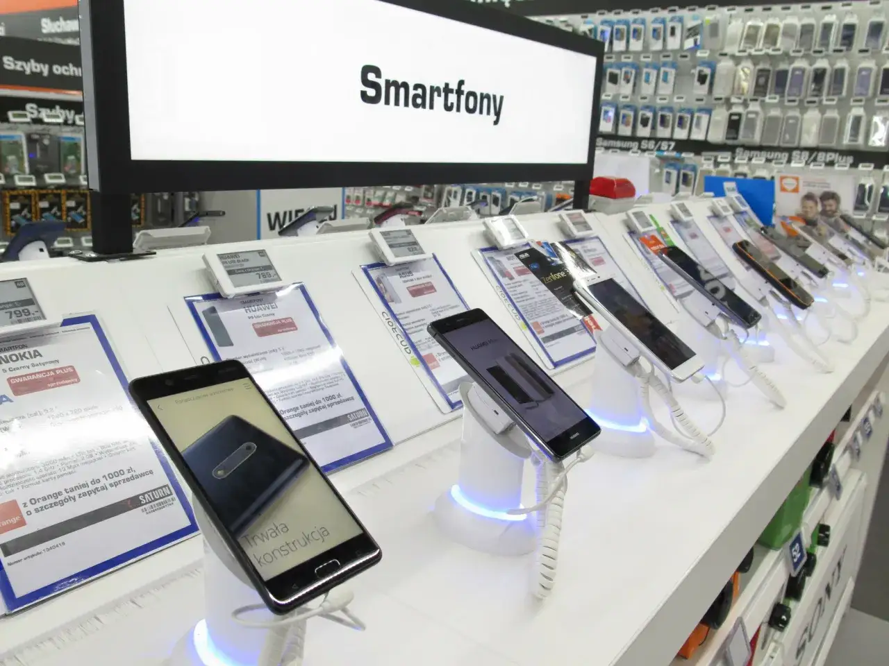 W sklepie z elektroniką wystawione są smartfony. Na ekranie widnieje napis