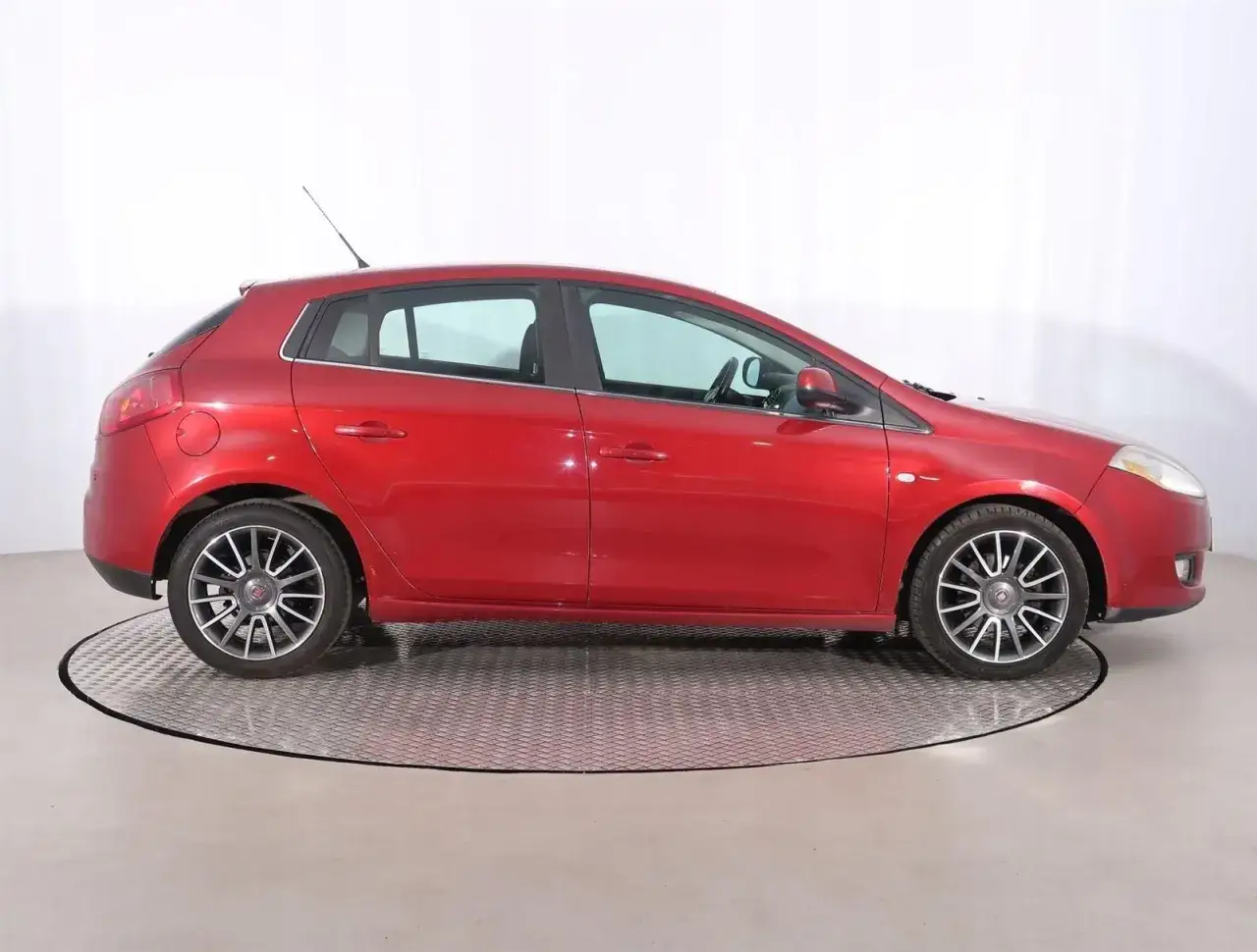 Czerwony Fiat Bravo 1.4 T-Jet na obrotowej platformie, widok z boku.