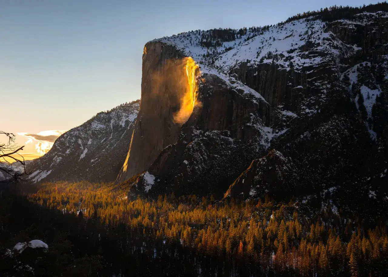 El sol poniente ilumina una cascada de fuego en Yosemite, creando un espect&aacute;culo dorado sobre la nieve y los pinos.