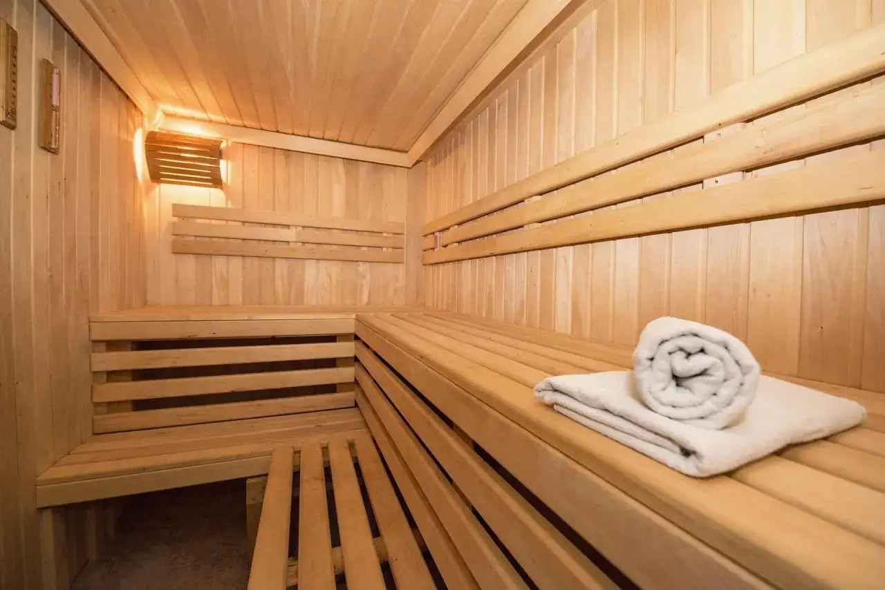 Drewniana sauna z ławkami i ręcznikiem. Czy sauna po treningu jest zdrowa? Tak, to świetny sposób na relaks i regenerację.