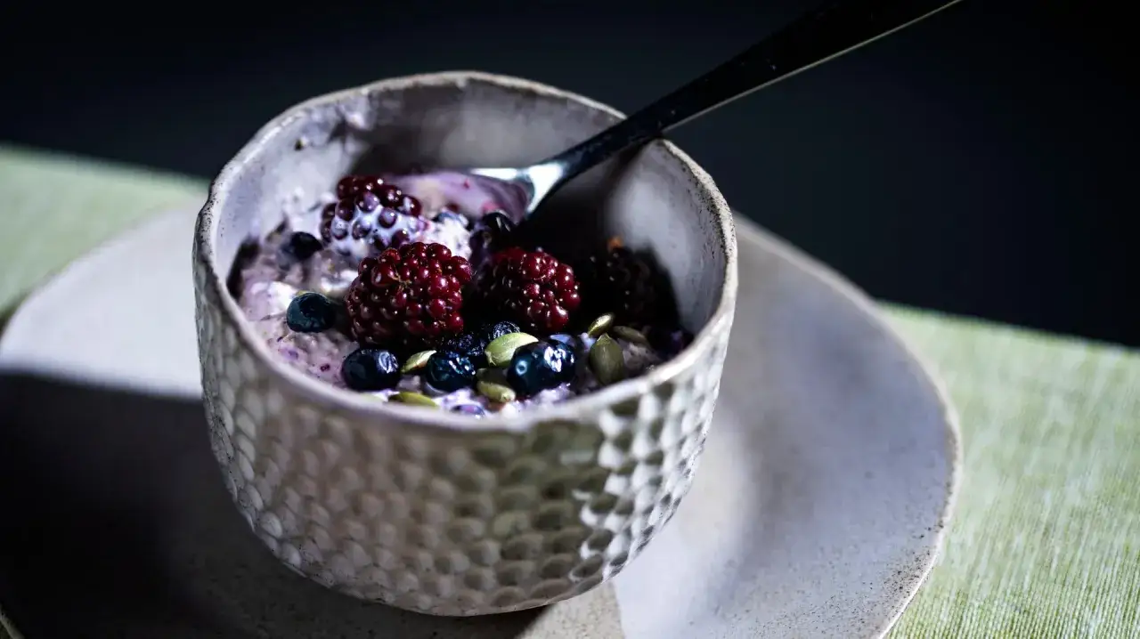 En skål med overnight oats toppad med björnbär, blåbär och pumpafrön. Perfekt för en snabb och näringsrik frukost.