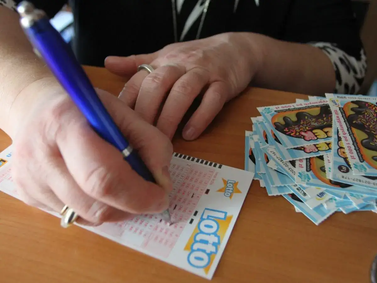 Ręka z długopisem zaznacza liczby na kuponie Lotto. Obok stos zdrapek. Jakie są szanse na trafienie tej samej kombinacji liczb dwa razy z rzędu?