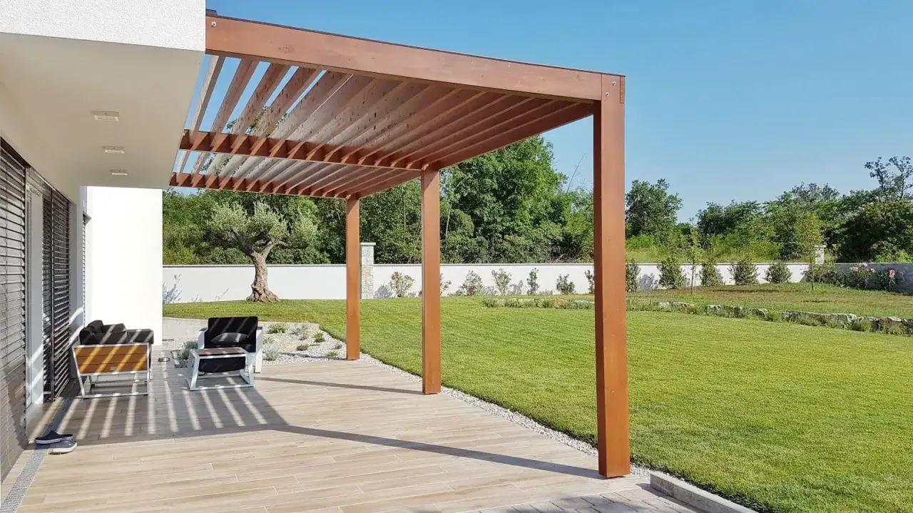 Nowoczesna pergola nad tarasem, z meblami wypoczynkowymi. Czy zabudowa tarasu wymaga pozwolenia na budowę?