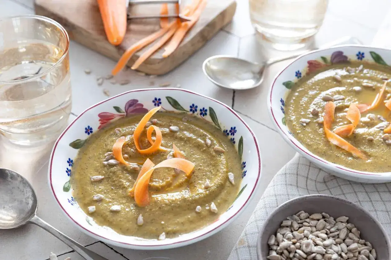 Deux bols de soupe de lentilles, garnie de carottes r&acirc;p&eacute;es et de graines de tournesol. Un verre d'eau et des carottes sur une planche compl&egrave;tent la sc&egrave;ne.