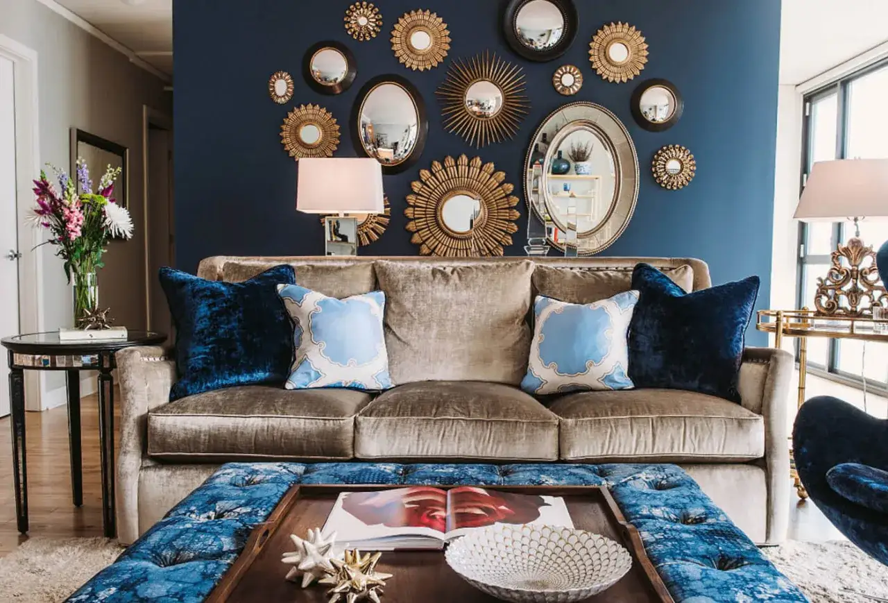 Luxuriöse Wandgestaltung mit vielen Spiegeln in Gold und Schwarz. Ein tiefblauer Teppich und Kissen ergänzen den samtigen braunen Sofa. Tolle Wand-Inspo!