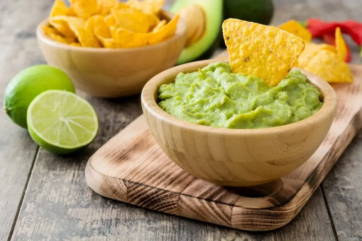 Pyszne guacamole co to? Kremowy dip z awokado, limonki i chipsów tortilla na drewnianym stole.