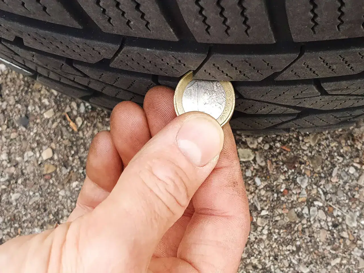 Ein Euro-Stück wird genutzt, um die Mindestprofiltiefe eines Motorradreifens zu prüfen.