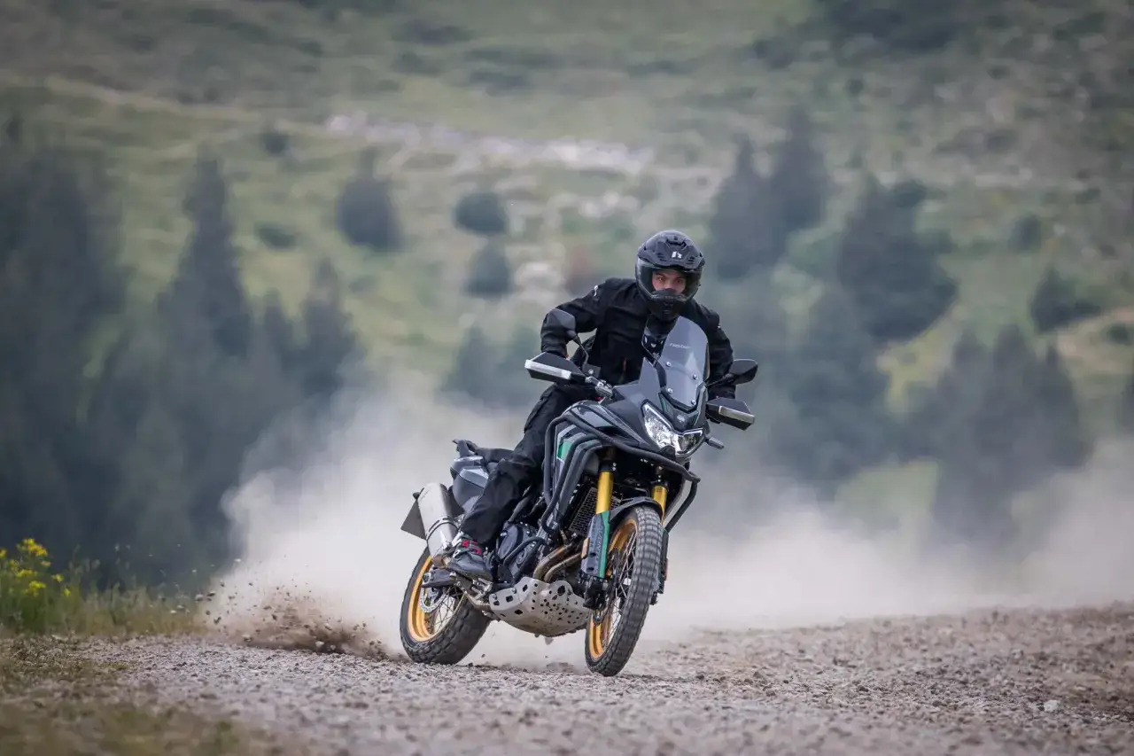 Motociclista en una Rieju Aventura 500, levantando polvo en un camino de grava. La ficha técnica de esta moto es impresionante.