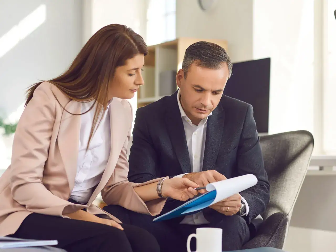 Profesionales revisan un documento, discutiendo una posible **modificación de contrato** en una oficina moderna.