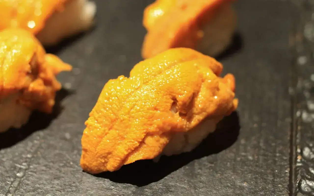Ein Sushi-St&uuml;ck mit leuchtend orangefarbenem Seeigel. Wer fragt, wie schmeckt Seeigel? Cremig, leicht salzig, ein Hauch von Meer.