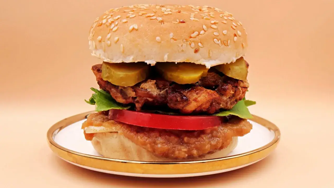Pyszny burger z kurczakiem, ogórkiem, pomidorem i sałatą. Zastanawiasz się, ile kalorii ma burger? Ten wygląda na sycący!