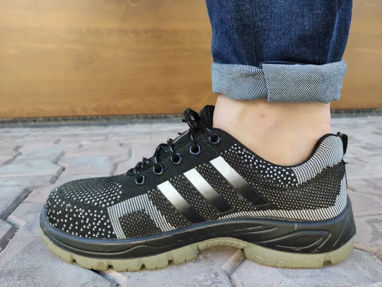 Pokazano, jak podwinąć spodnie, aby odsłonić kostkę i sportowe buty.
