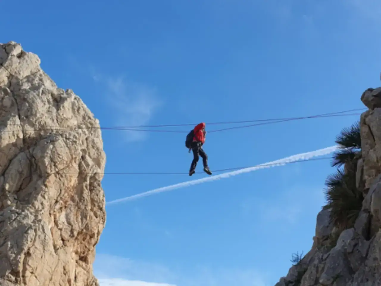 Persona cruza un puente colgante en el Caminito del Rey, una vía ferrata espectacular entre riscos.