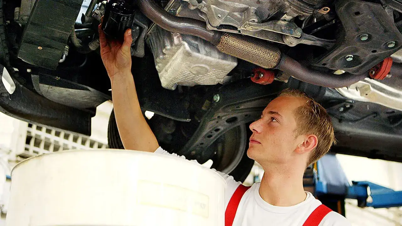 Mechaniker wechselt &Ouml;lfilter unter dem Auto. Informieren Sie sich &uuml;ber den fairen stundensatz kfz werkstatt f&uuml;r Ihren n&auml;chsten Service.