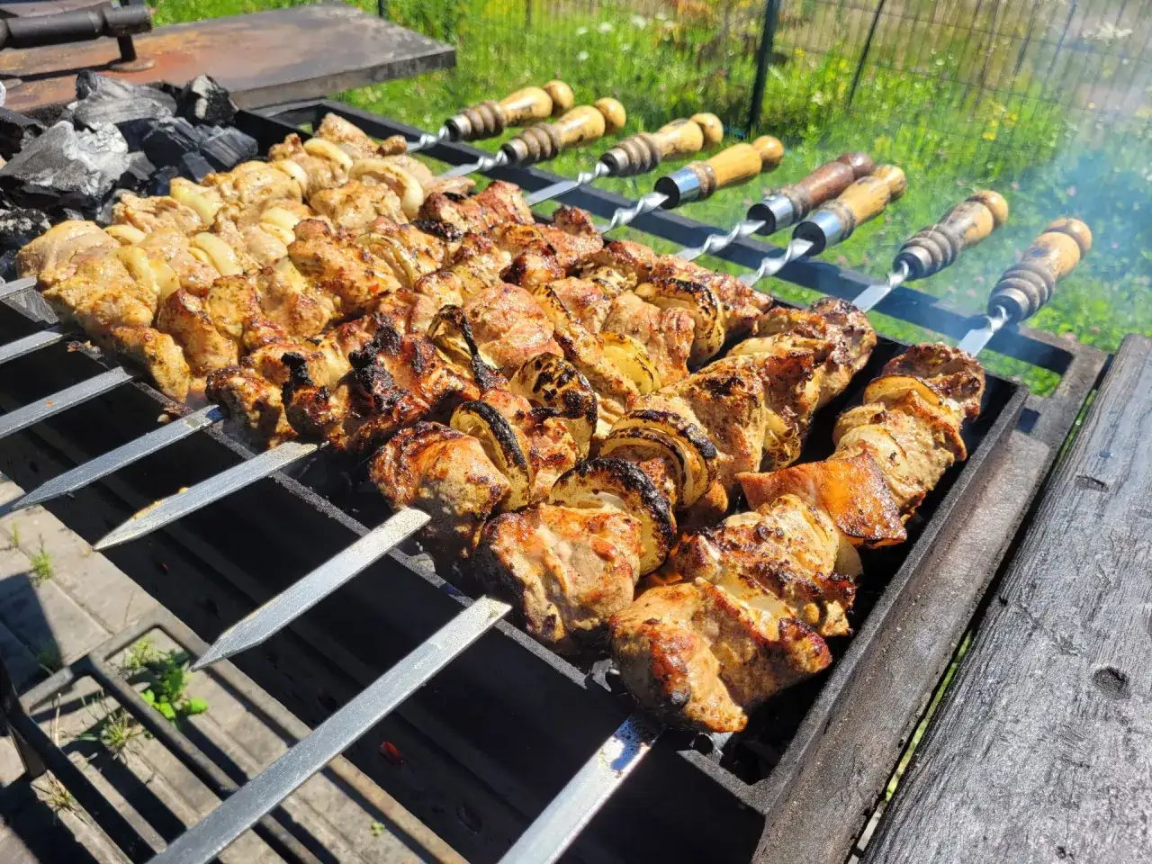 Fleischspie&szlig;e mit Zwiebeln auf einem Grill, die nach dem besten russischen Schaschlik Rezept zubereitet werden.
