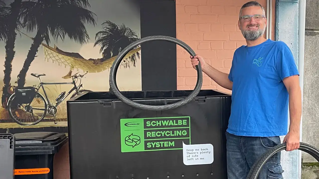 Mann hält Fahrradreifen vor Schwalbe Recycling System. So wird Fahrradschlauch Recycling zum Kinderspiel.