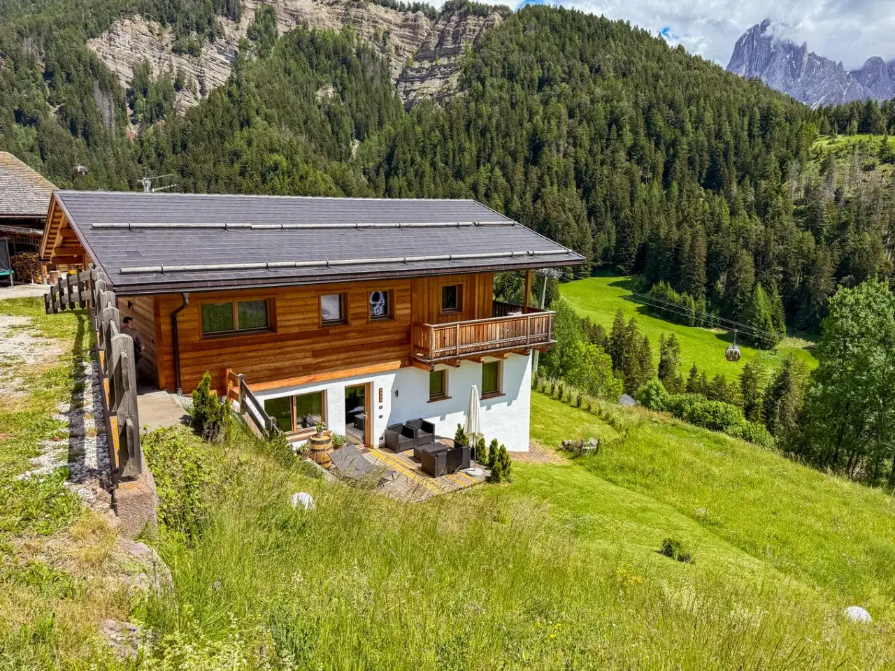 Maso Gallo Rosso, un'accogliente baita in legno e pietra, immersa nel verde dei prati alpini e circondata da una fitta foresta.