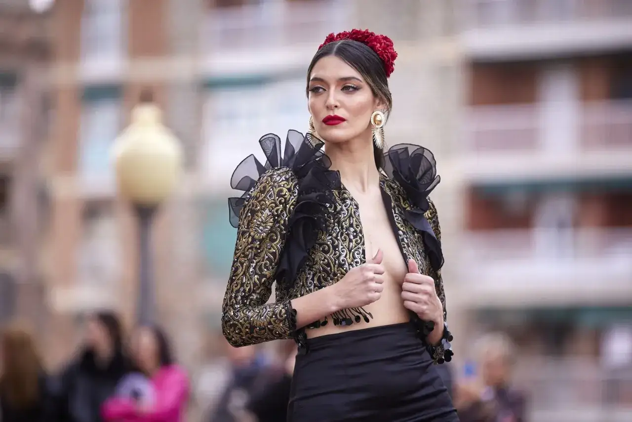 Una mujer luce un elegante bolero con volantes y bordados dorados, parte de los diversos tipos de vestidos de flamenca.