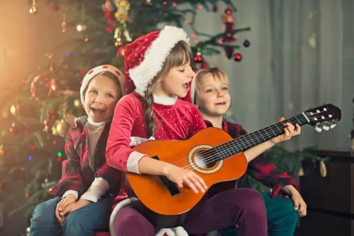 Ni&ntilde;os cantan villancico flamenco para ni&ntilde;os junto a un &aacute;rbol de Navidad.