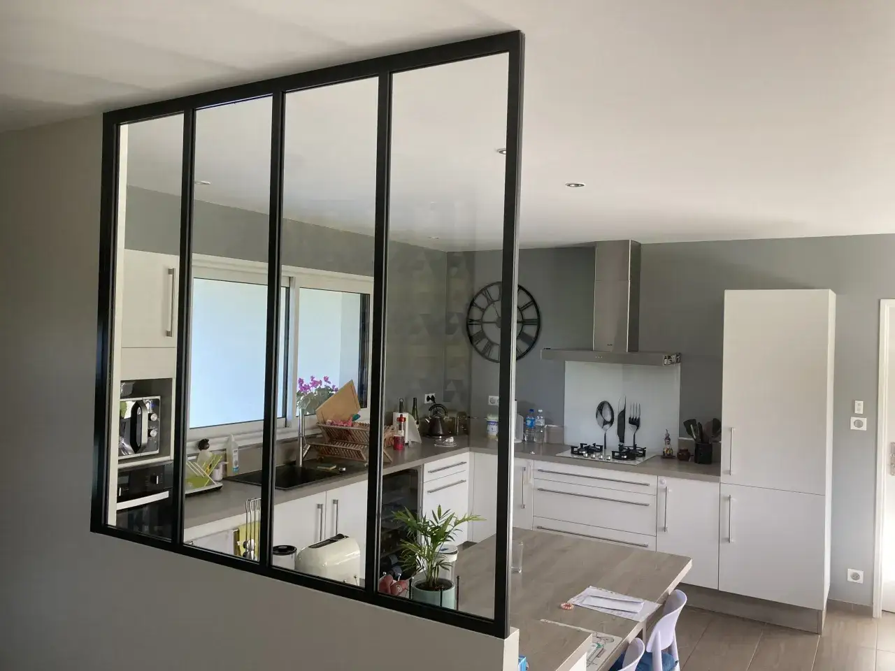 Une cuisine moderne s&eacute;par&eacute;e par une verri&egrave;re noire. Id&eacute;al pour savoir comment installer une verri&egrave;re et moderniser votre int&eacute;rieur.