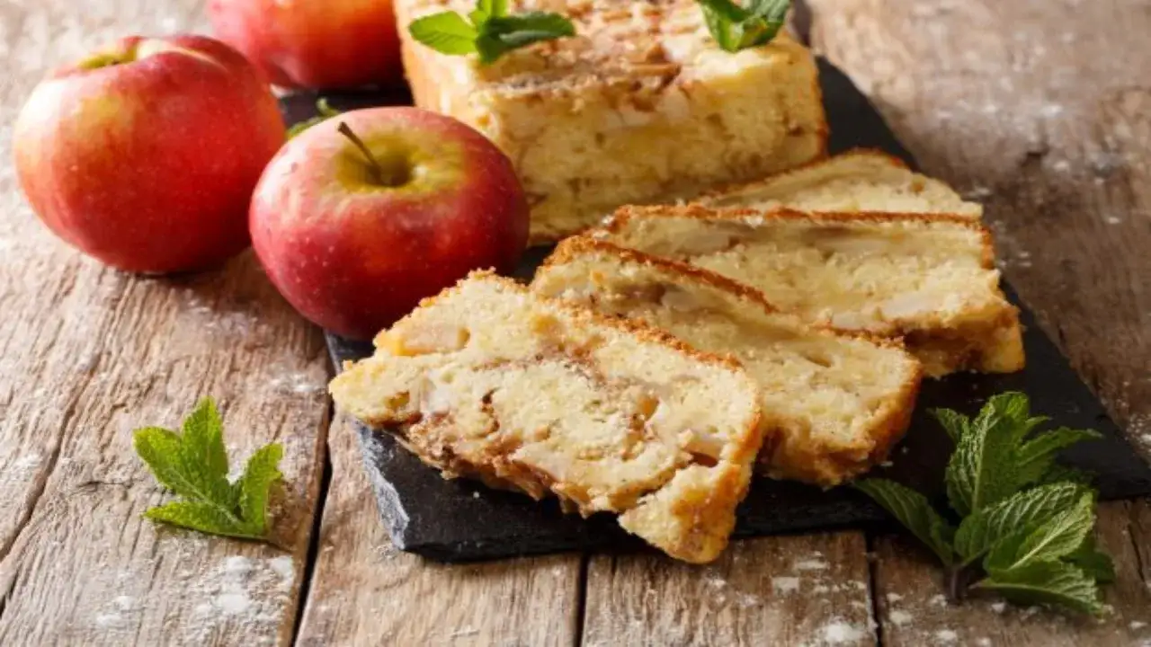 Gâteau pomme bébé sans sucre, moelleux et parfumé, avec des pommes fraîches et des feuilles de menthe sur fond de bois.