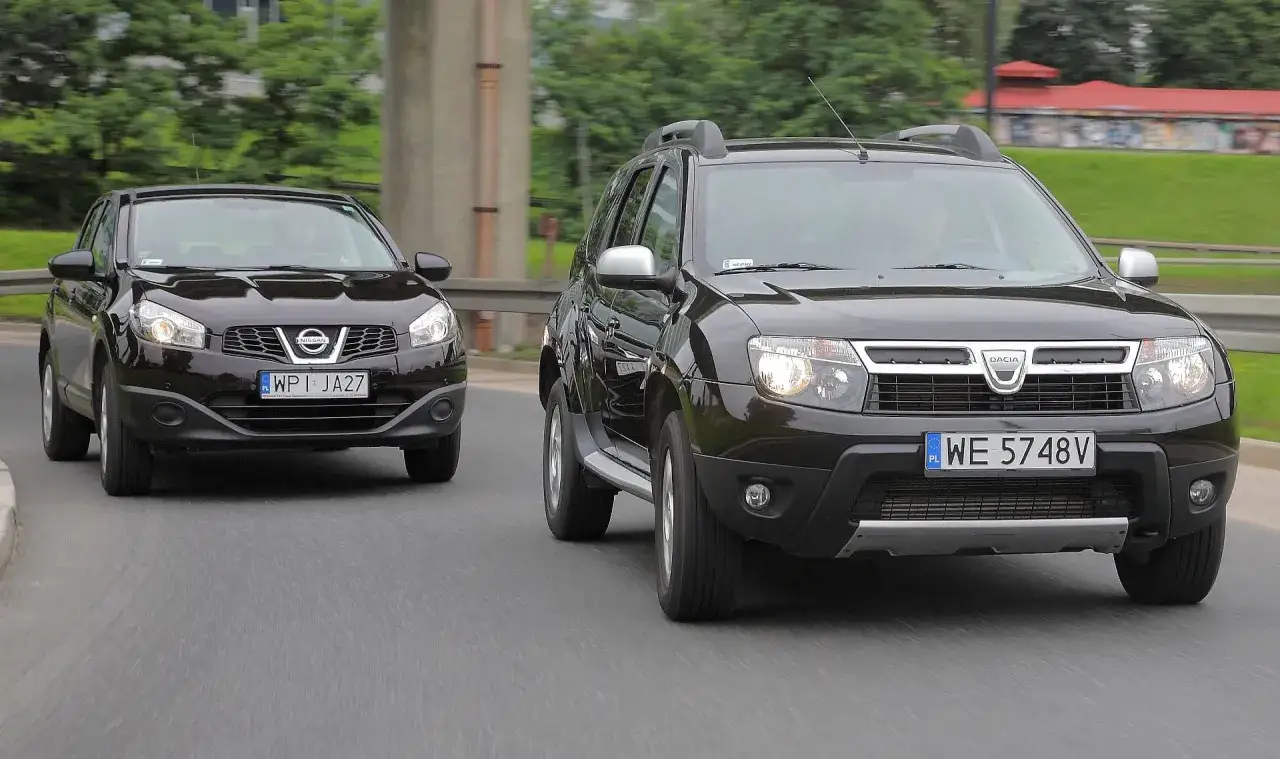 Dwa czarne SUV-y jadące drogą. Z przodu Dacia Duster, za nią Nissan Qashqai. Duster to suv z fabrycznym LPG.