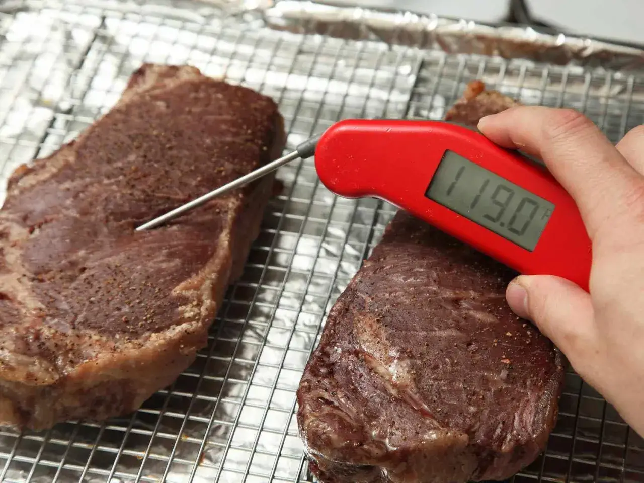 Perfekt gegrilltes Cowboy Steak: Ein rotes Thermometer misst die Kerntemperatur von 119°F.