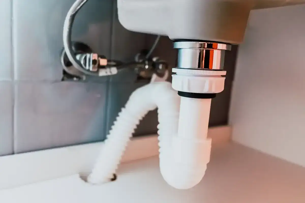 D&eacute;tail du schema montage bonde lavabo : raccordement du siphon et du tuyau d'&eacute;vacuation flexible sous un &eacute;vier.