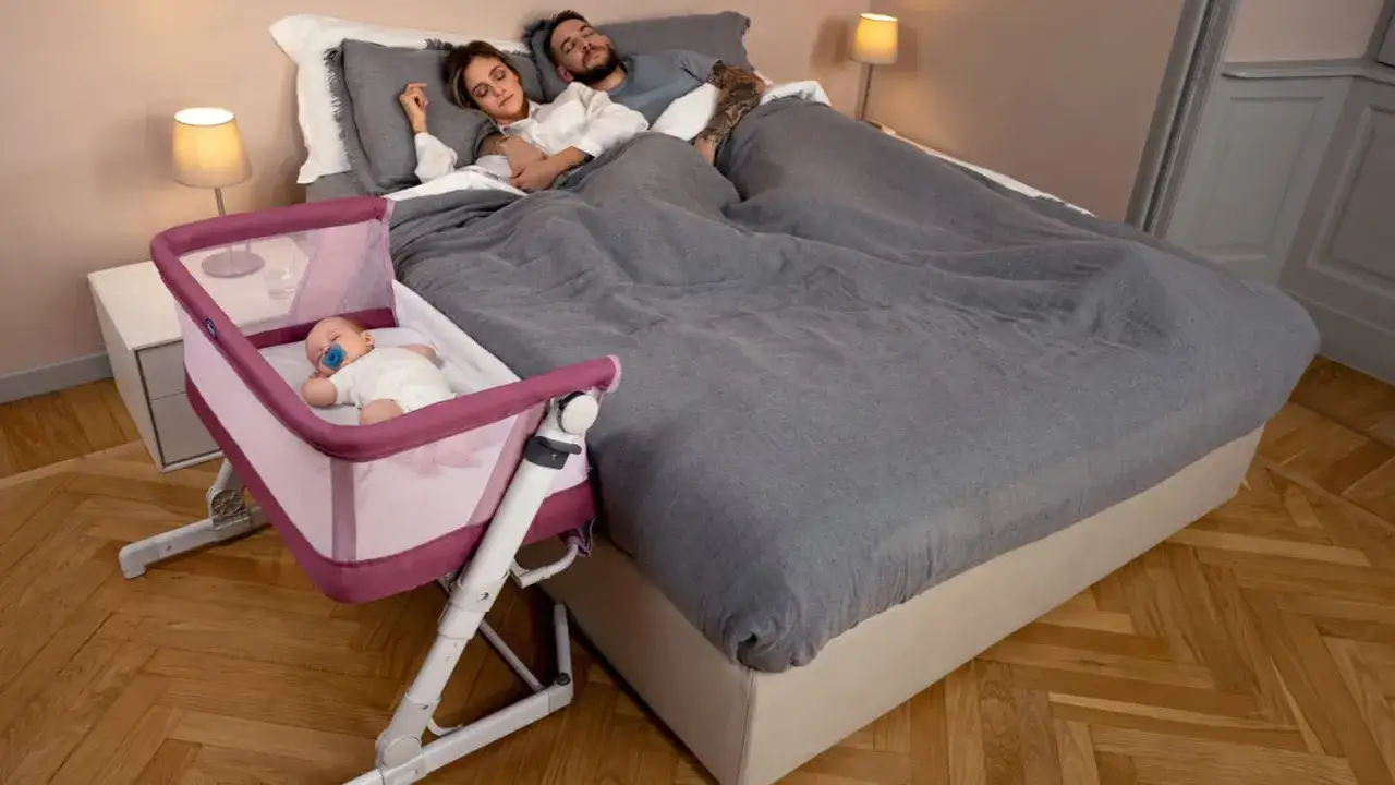 Un beb&eacute; de 2 meses duerme pl&aacute;cidamente en su minicuna junto a sus padres, que tambi&eacute;n descansan en la cama.