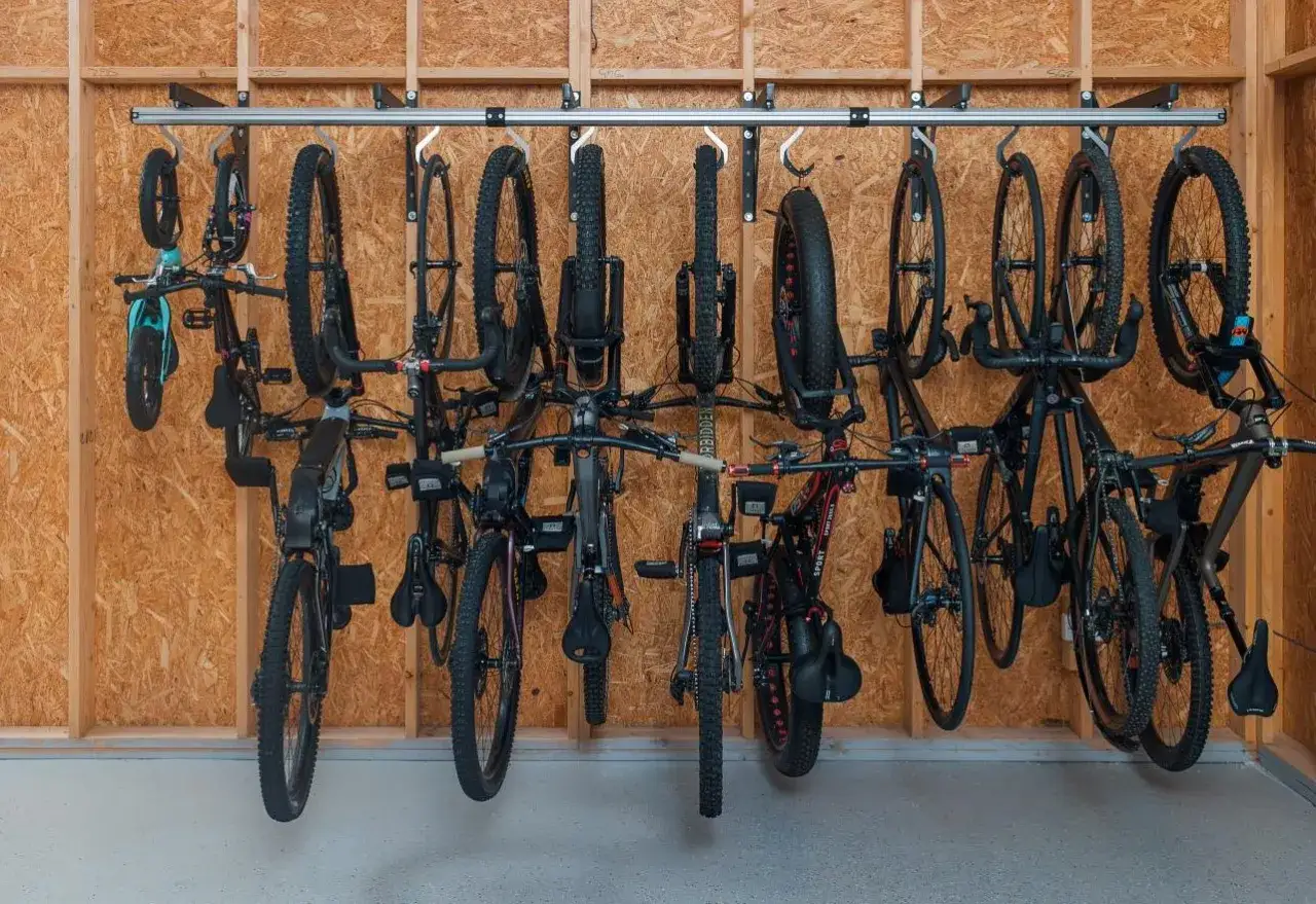A wall-mounted diy bike rack holds multiple bicycles, from road bikes to fat-tire mountain bikes, neatly organized and off the floor.