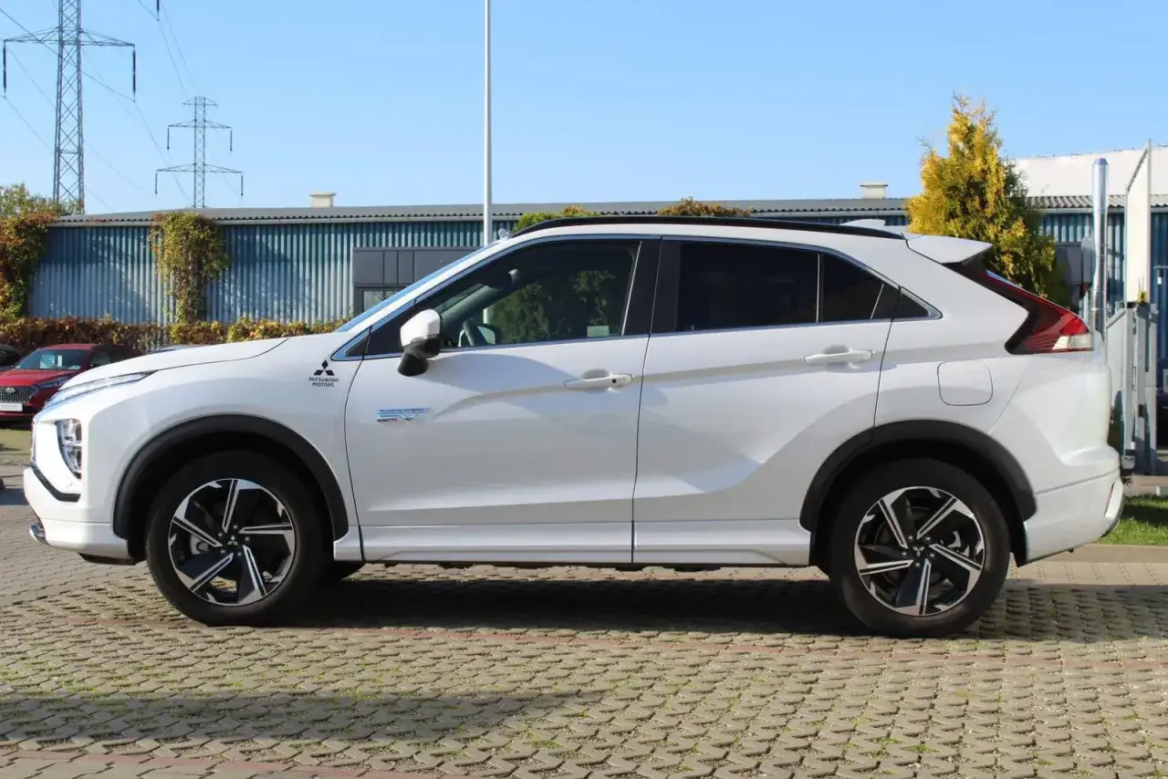 Biały Mitsubishi Eclipse Cross, nowoczesny crossover, zaparkowany na kostce brukowej.