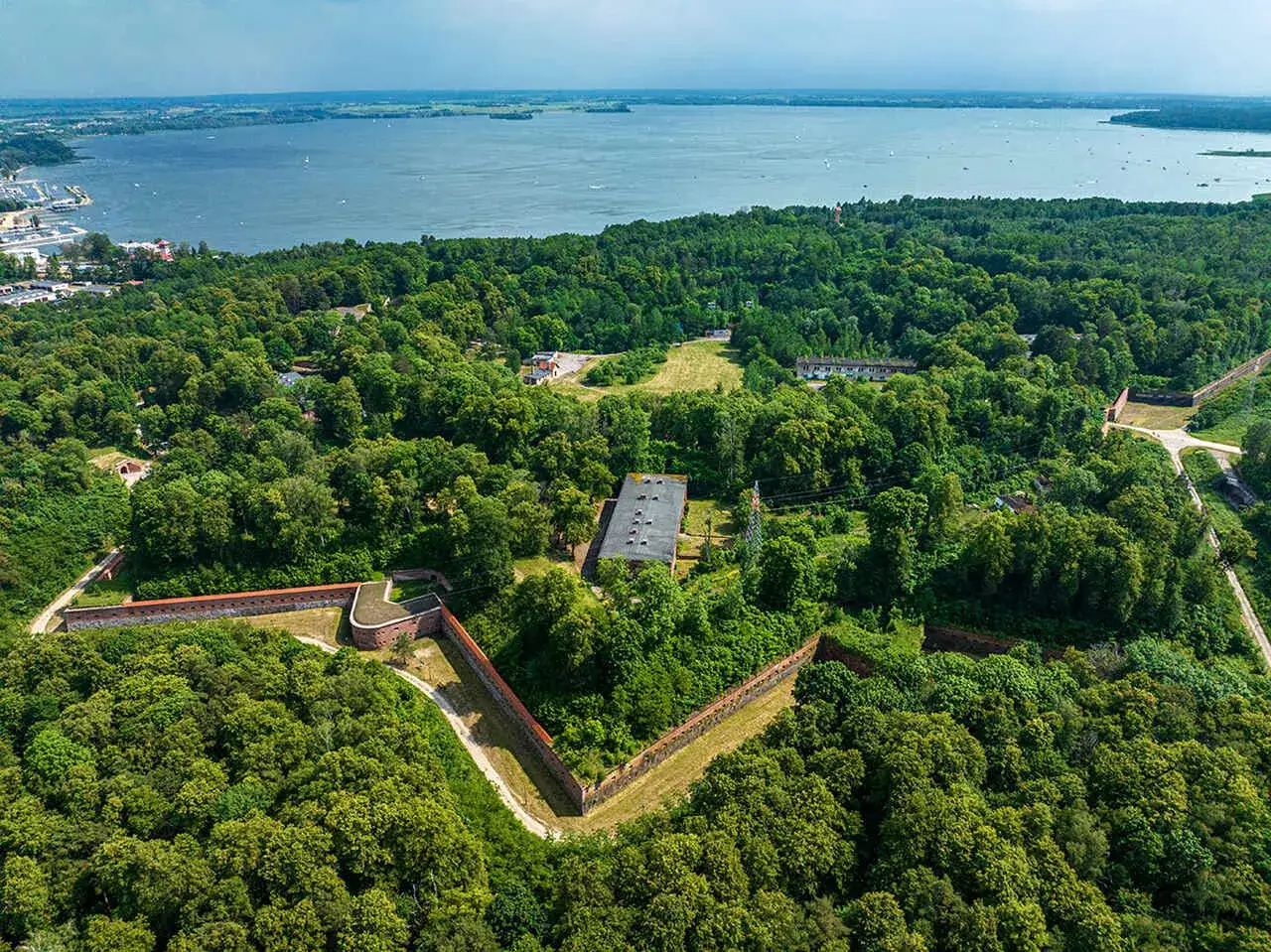 Fortyfikacje w otoczeniu zieleni, z widokiem na jezioro. To część szlaku wielkich jezior mazurskich trasa, idealna na odkrywanie historii.