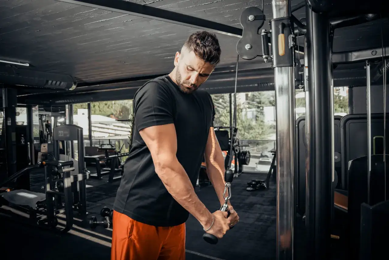 Mężczyzna ćwiczy triceps na maszynie. Zastanawiasz się, ile serii na triceps w tygodniu będzie optymalne?