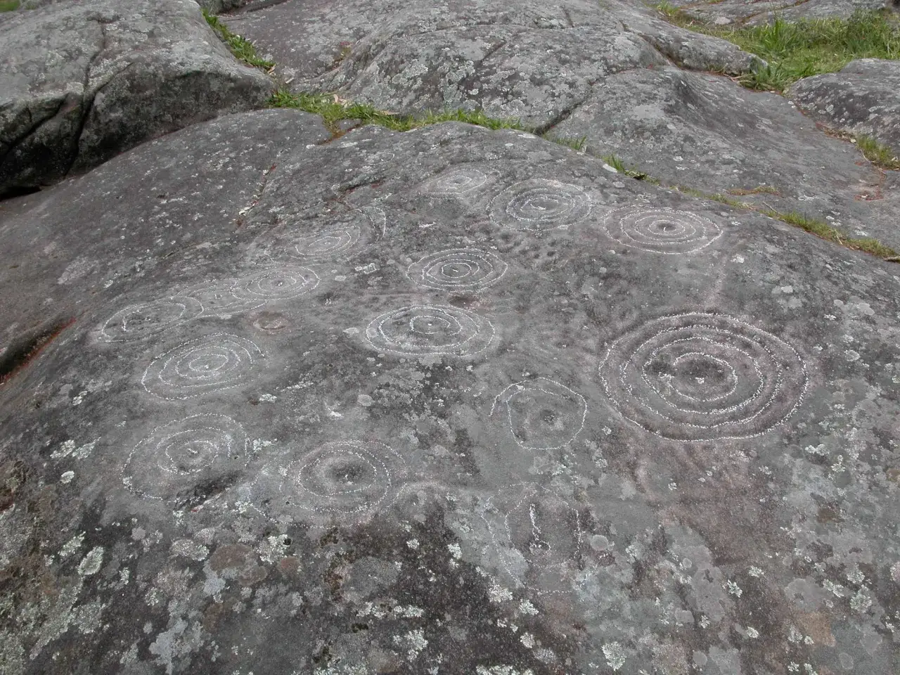 Petroglifos de Mogor: c&iacute;rculos conc&eacute;ntricos grabados en roca, testigos de un pasado ancestral.