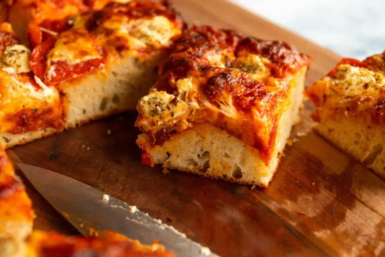 Saftige Pizza-Stücke mit geschmolzenem Käse und Tomatensoße, frisch aus dem Pizzafunktion Ofen, liegen auf einem Holzbrett.