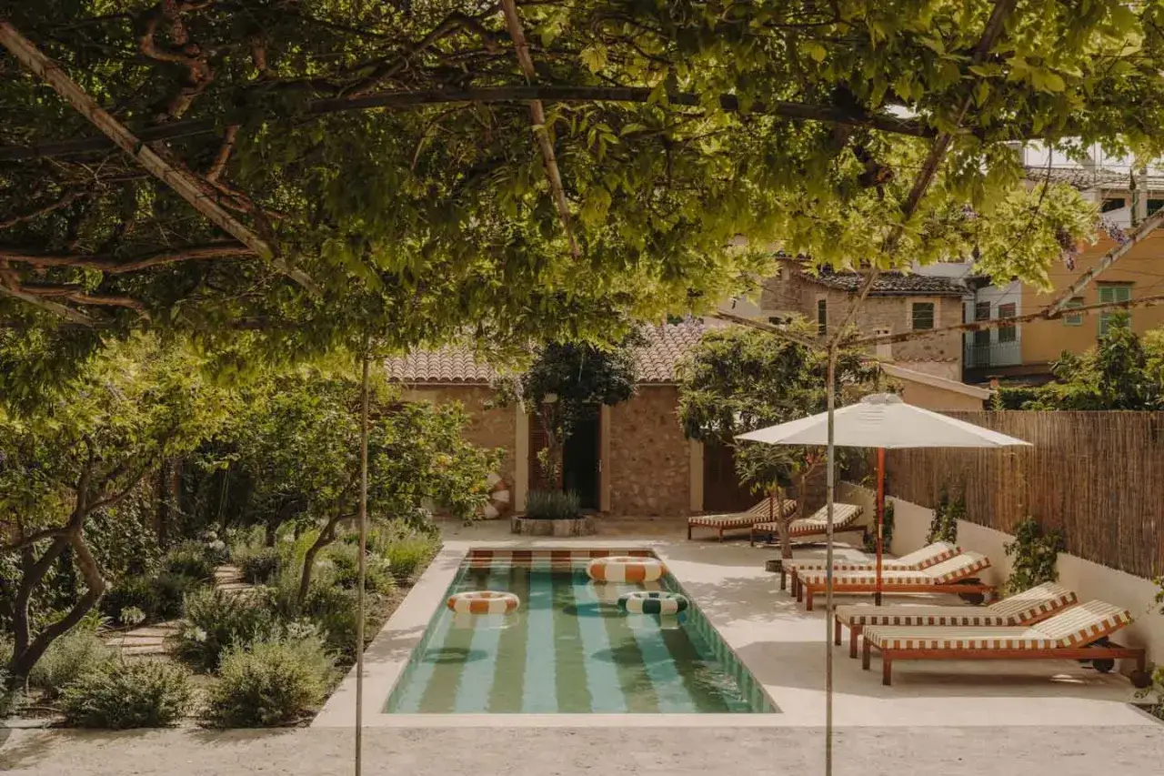 Idee piccoli giardini con piscina: una oasi rilassante con lettini, ombrellone e galleggianti colorati, immersa nel verde.