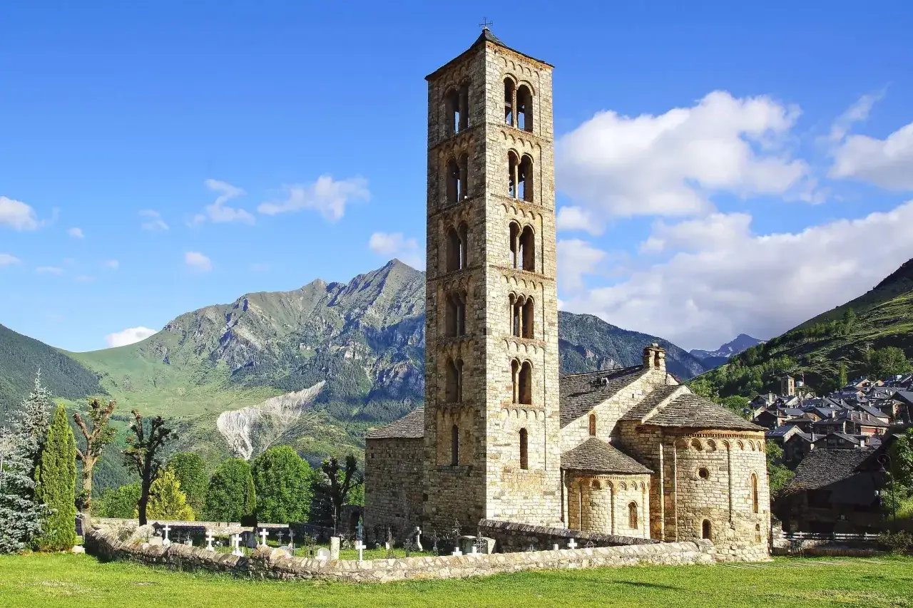 La iglesia de la Magdalena, con su torre románica, se alza majestuosa ante montañas verdes.