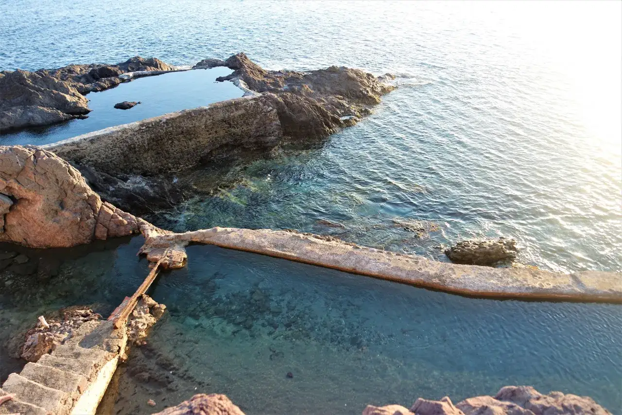 Piscinas naturales de roca en Cabo de Gata en octubre, con aguas cristalinas y el sol reflej&aacute;ndose en el mar.