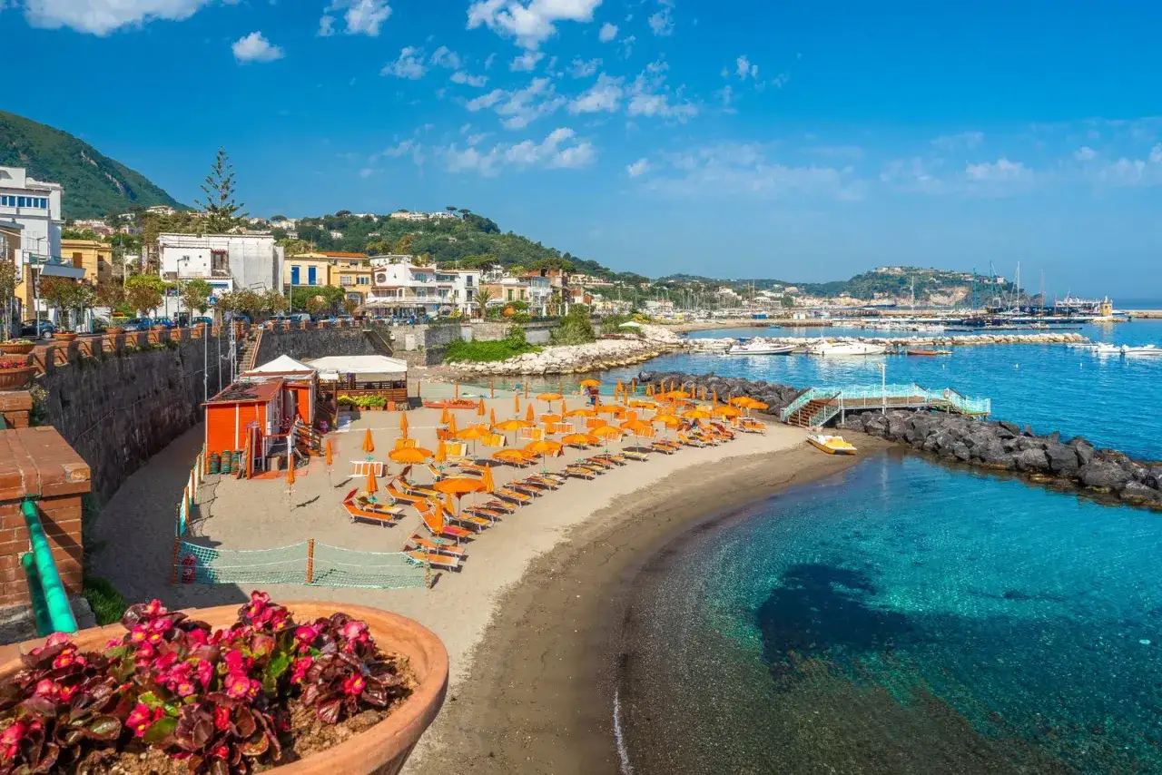 La spiaggia della marina &egrave; un incanto: sabbia dorata, ombrelloni arancioni, mare cristallino e un porto pieno di barche.
