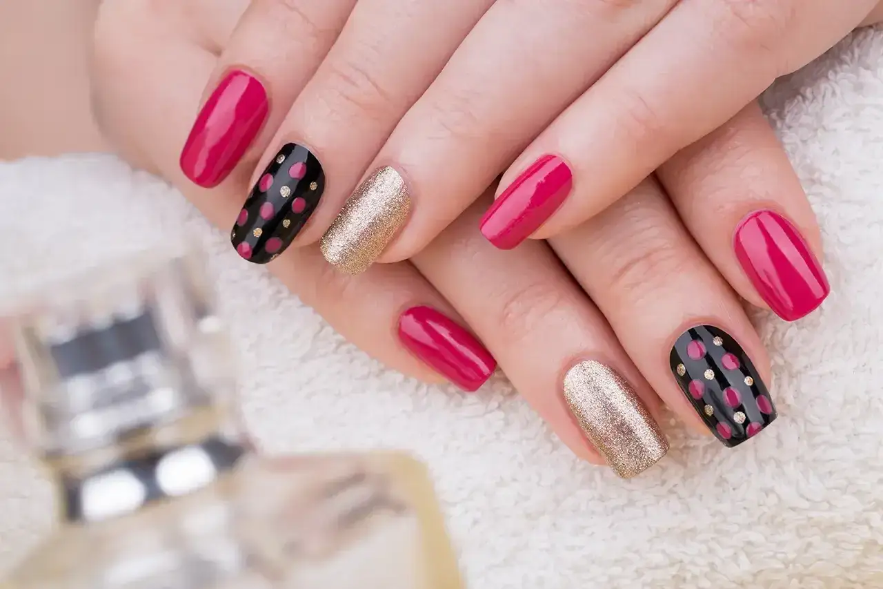Mani curate con unghie decorate con gel polish: rosa acceso, nero a pois rosa e oro scintillante.