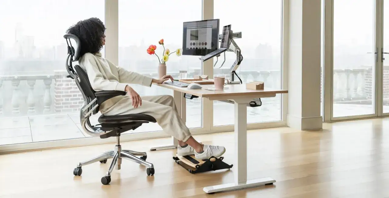 Une femme profite d'un espace de travail moderne, ax&eacute; sur l'ergonomie du bureau, avec un fauteuil confortable et un repose-pieds.