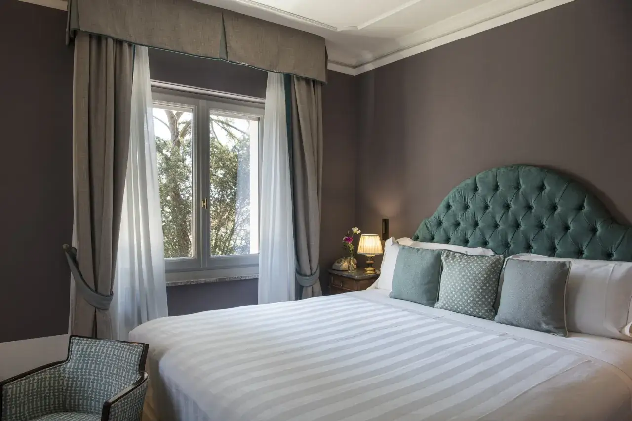 Camera elegante con letto king size, testiera capitonn&eacute; verde acqua e vista sul giardino. Ottime idee nomi camere per un soggiorno da sogno.