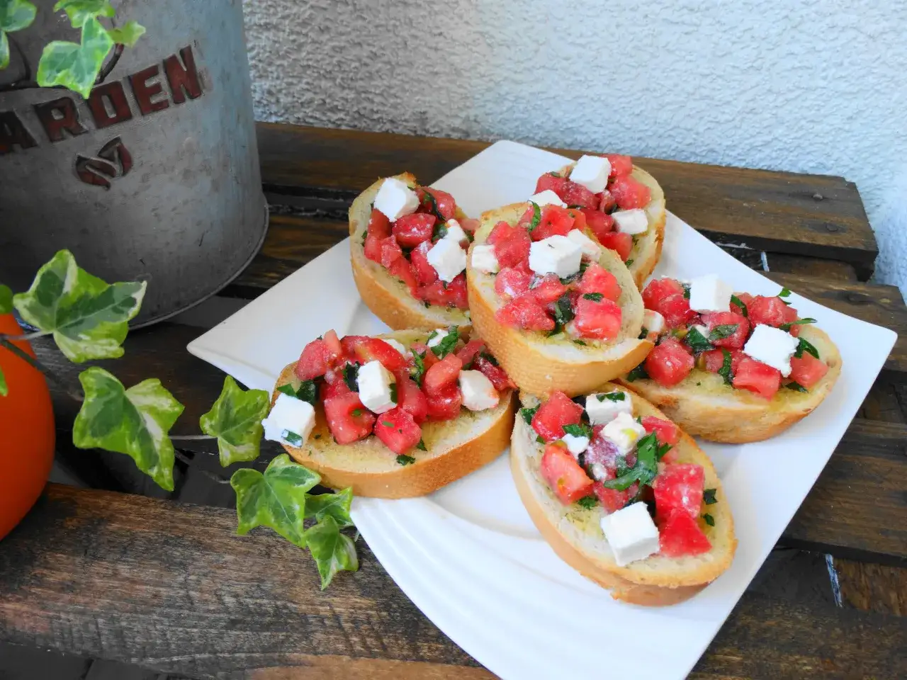 Pyszna ser bruschetta z pomidorami i ziołami na chrupiącej bagietce, podana na białym talerzu.