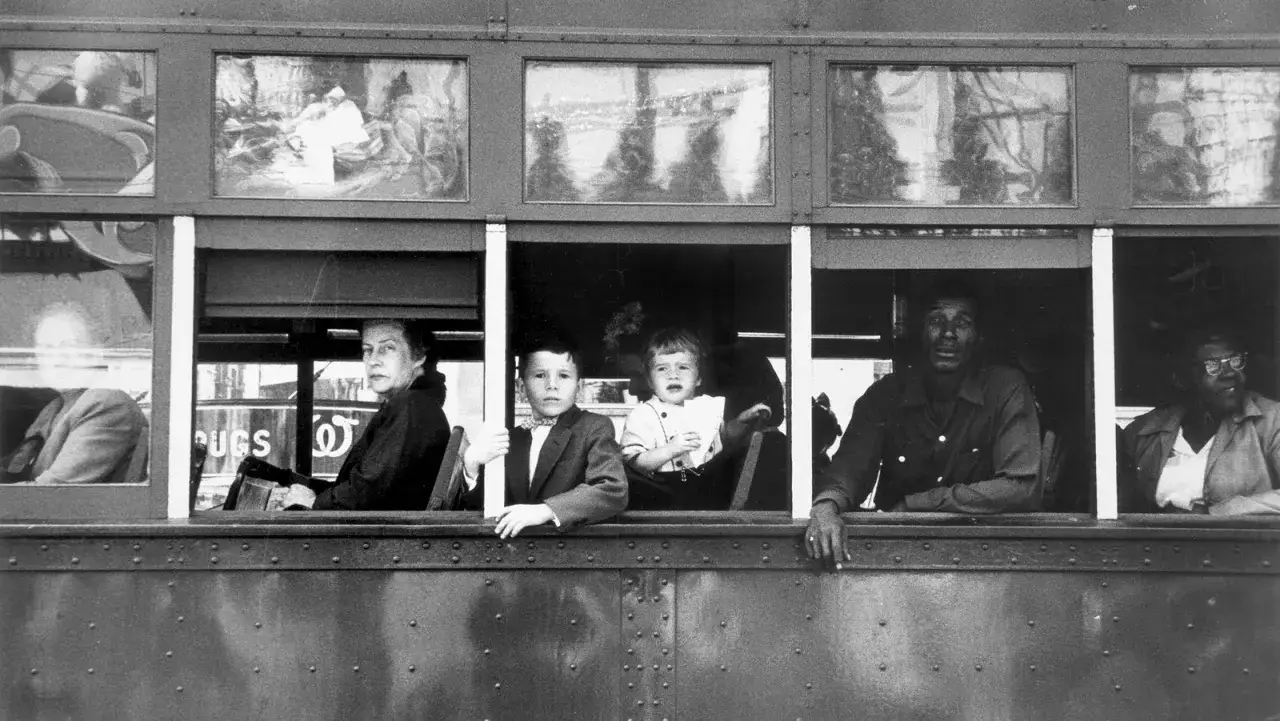 Osoby w oknie tramwaju, uchwycone przez Roberta Franka. Widać twarze dzieci, kobiety i mężczyzn, każdy z własną historią.