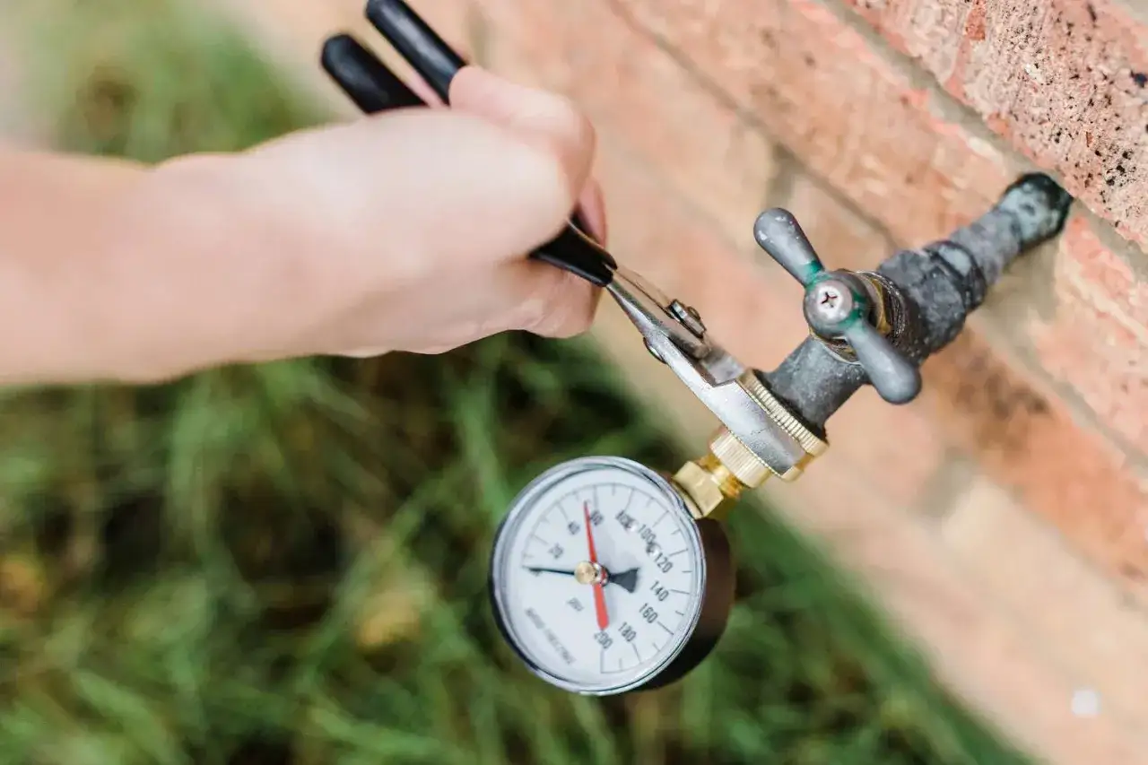 Mesure de la pression eau maison : le manomètre indique environ 4 bars. Un outil est utilisé pour le raccordement.
