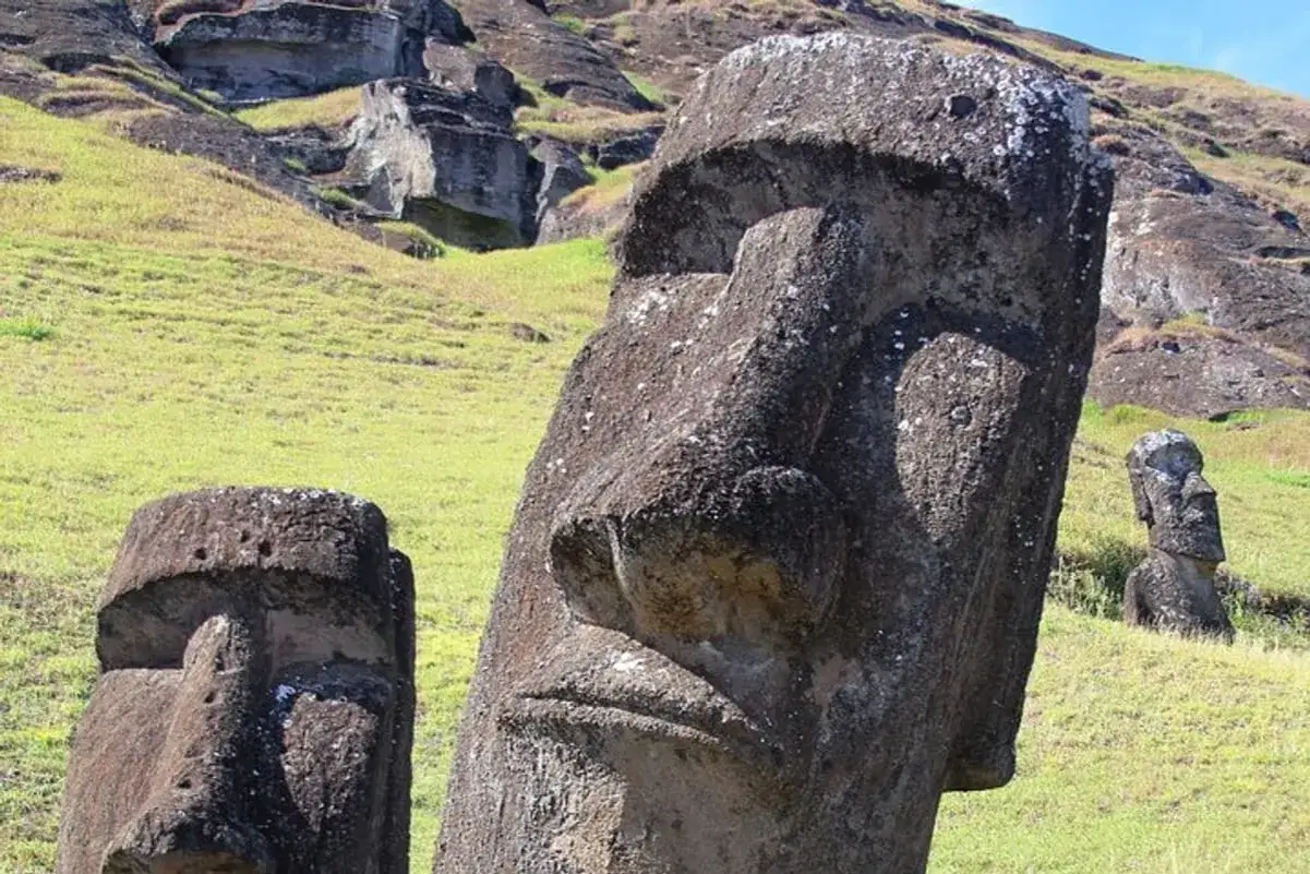 Kamienne posągi Moai na Wyspie Wielkanocnej, która należy do Chile, stoją na zielonym wzgórzu.