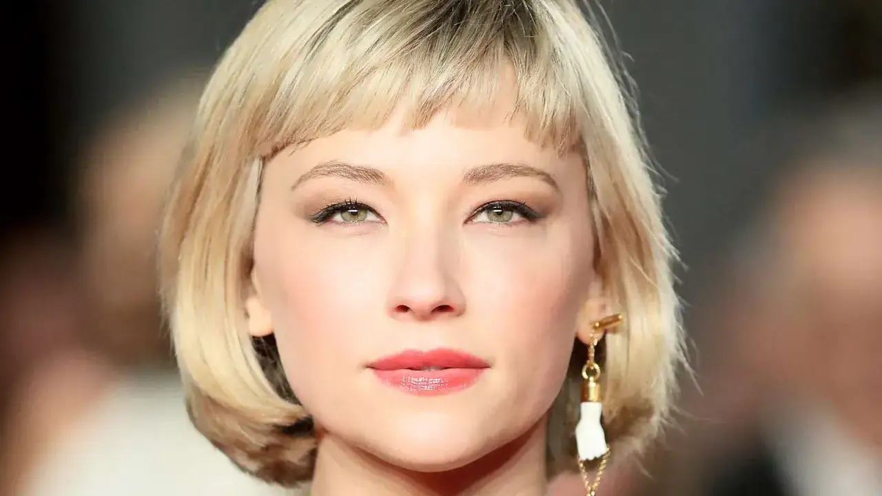 Ein kurzer Bob mit Curtain Bangs umrahmt das Gesicht einer Frau mit grünen Augen und einem dezenten Lächeln.
