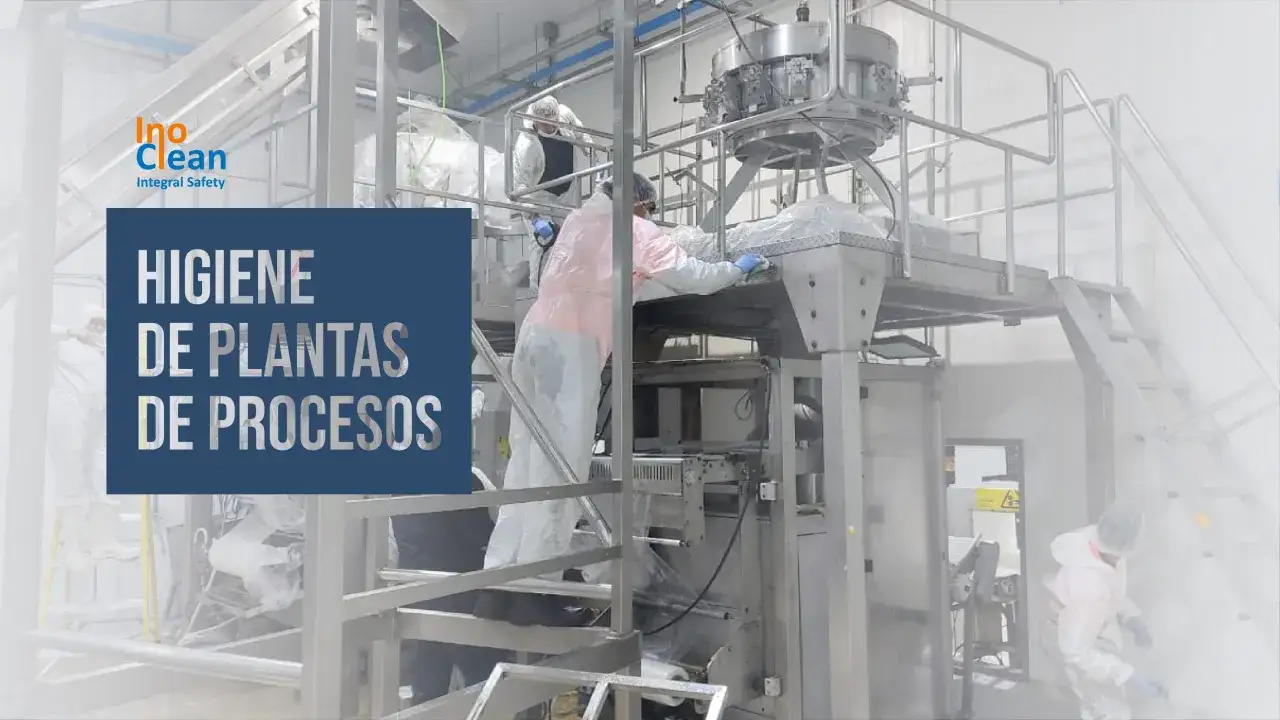 Trabajadores con trajes protectores limpian maquinaria industrial. El **asepsia significado** es clave para la higiene de plantas de procesos.
