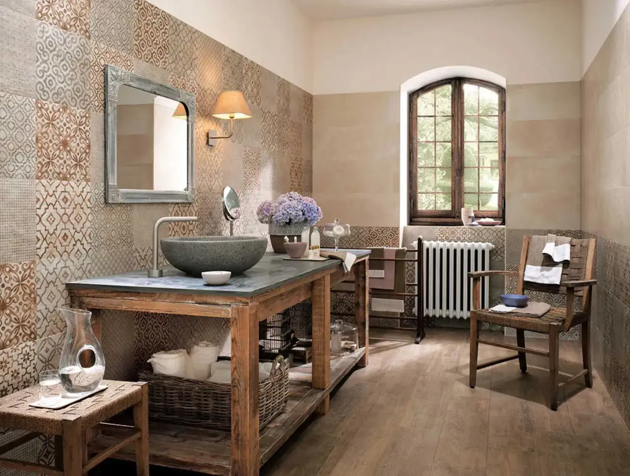 Bagni rustici di campagna con lavabo in pietra, specchio antico e pareti decorate con piastrelle a motivi geometrici.